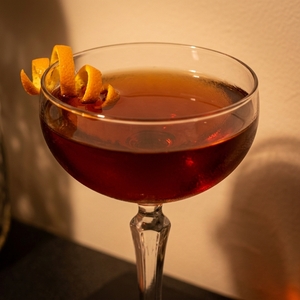 An image of the Fall Back cocktail submitted by n0tquitethere that contains Rye Whiskey, Apple Brandy, Amaro Nonino, Sweet Vermouth, Peychauds Bitters and Orange