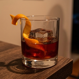 An image of the Heavy Artillery cocktail submitted by n0tquitethere that contains Rye Whiskey, Smith & Cross, Green Chartreuse, Sweet Vermouth, Cinnamon Syrup, Demerara Syrup, Whiskey Barrel Aged Bitters and Orange